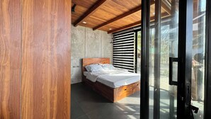 Un dormitorio moderno con techo de madera, una cama grande y un ventanal corredero que da a un espacio al aire libre.