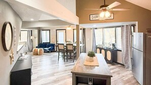 Un'ampia zona giorno con tavolo da pranzo, una cucina con frigorifero e una ventola a soffitto.