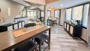 Un'ampia cucina con tavolo in legno, angolo caffè e grandi finestre con persiane.