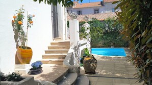 A courtyard with a pool, potted plants, and a white building. - Chambre d'hôtes in Demeure Remarquable / independent entrance (Béziers)