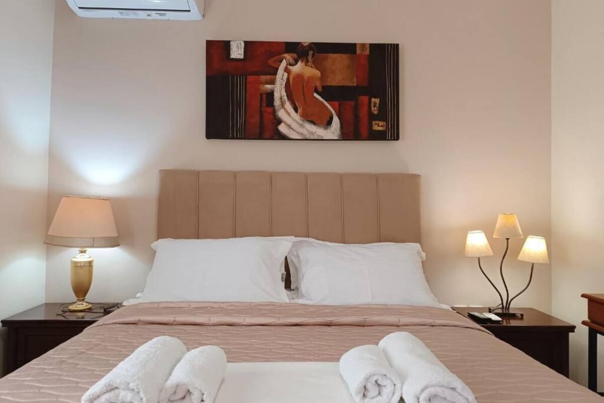 Une chambre d’hôtel avec un lit, deux tables de chevet, une lampe et un tableau au mur.