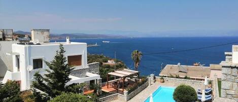 A residential property with a swimming pool, a patio area, and a view of the sea.