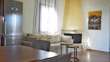Ein Wohnzimmer mit Sofa, kleinem Tisch, Kamin und Kühlschrank.