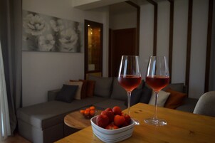 A dining table with a bowl of strawberries and two glasses of red wine.
