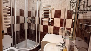 Une salle de bain moderne avec une douche à parois de verre, des toilettes, un lavabo avec un miroir et un porte-serviettes.