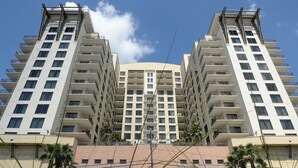Un immeuble moderne de grande hauteur, doté de nombreux balcons et d’un atrium central.