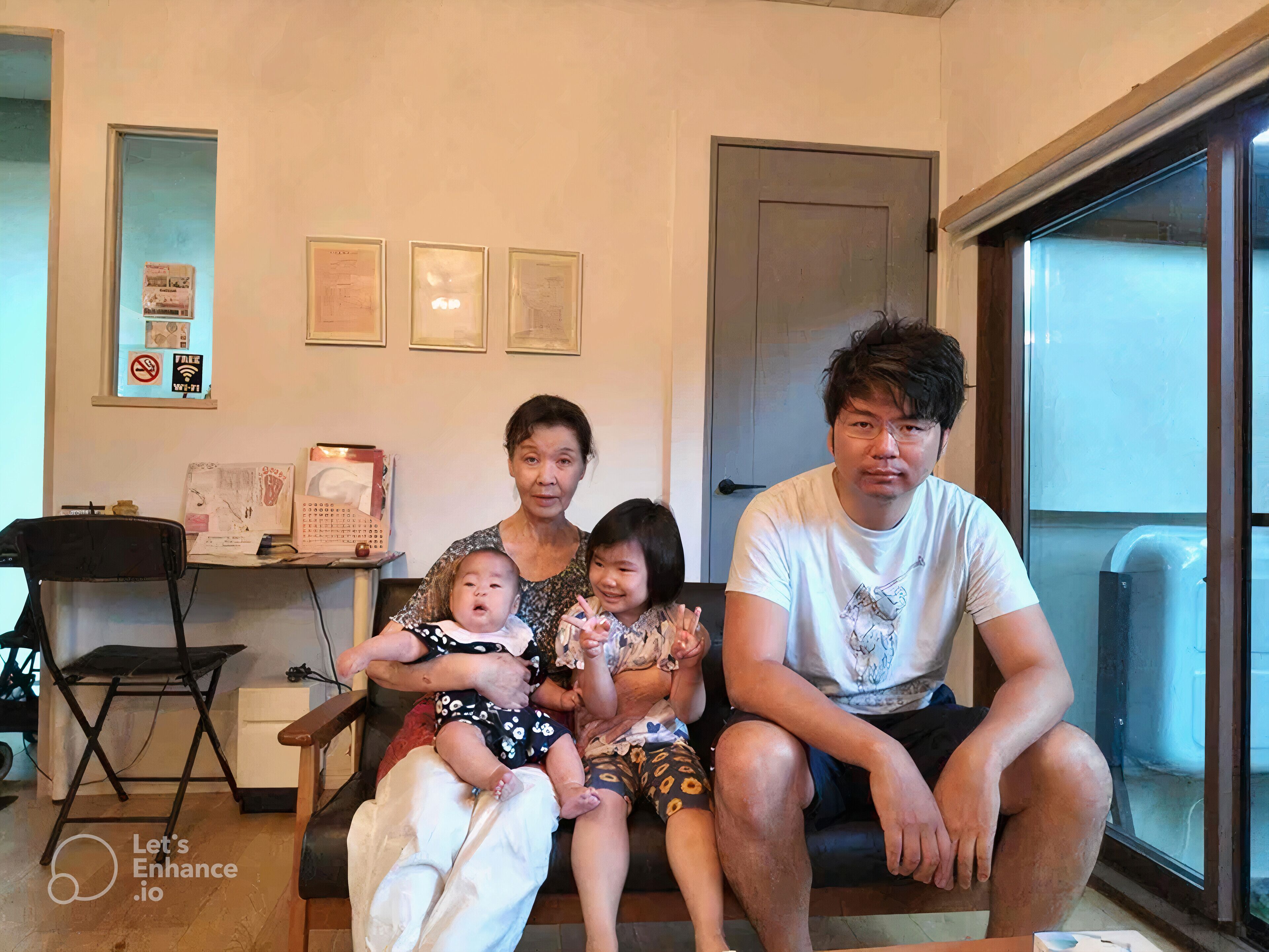 A family of four seated on a couch in a room with a door, a window, and a small table with papers and a calendar.