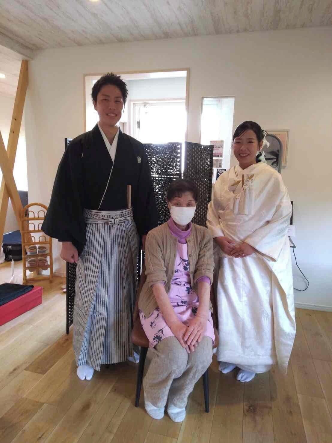 Una habitación con suelo de madera, una falda a rayas blancas y negras, una persona vestida con un kimono negro y otra con un kimono blanco.