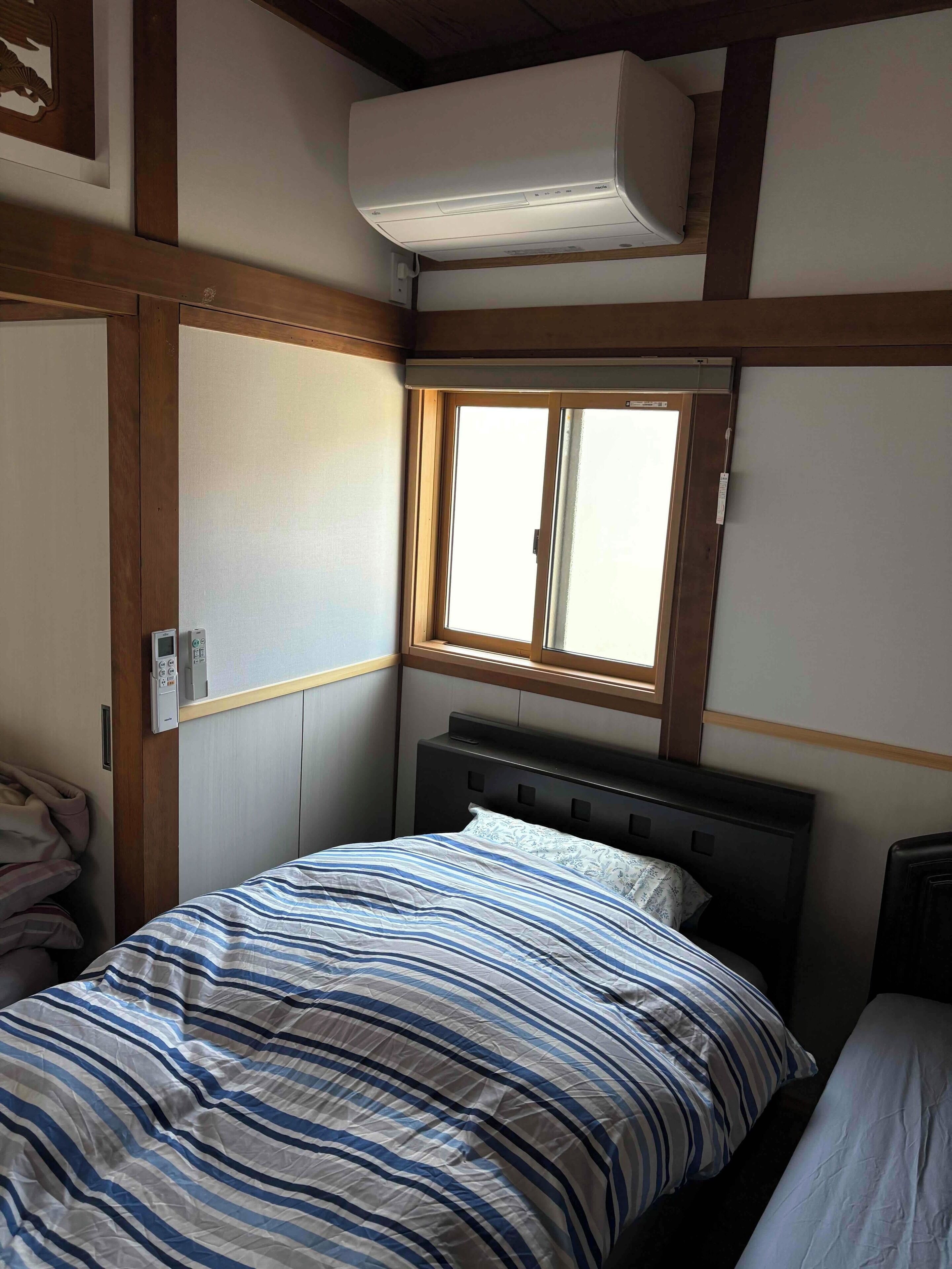 A bedroom with a bed, a window, and an air conditioning unit.