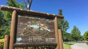 A wooden sign with a map and text, surrounded by trees and a clear sky.