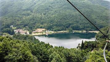 Un lago rodeado de bosque denso, con edificios y un bote amarrado a la orilla.