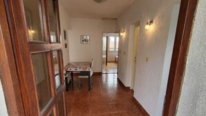 A hallway with a dining table and chairs, a ceiling light, and a door with glass panels. - Seaside Apartment Bubi (Crikvenica)