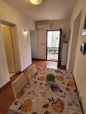 Ein Essbereich mit einer blumigen Tischdecke, Stühlen und einer Zimmerpflanze.