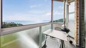Een balkon met een tafel en stoelen, uitzicht op de zee en een bakstenen muur.