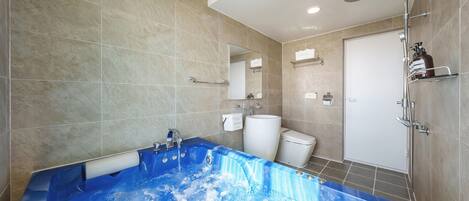 Un baño moderno con una bañera grande, un inodoro y una zona de ducha.