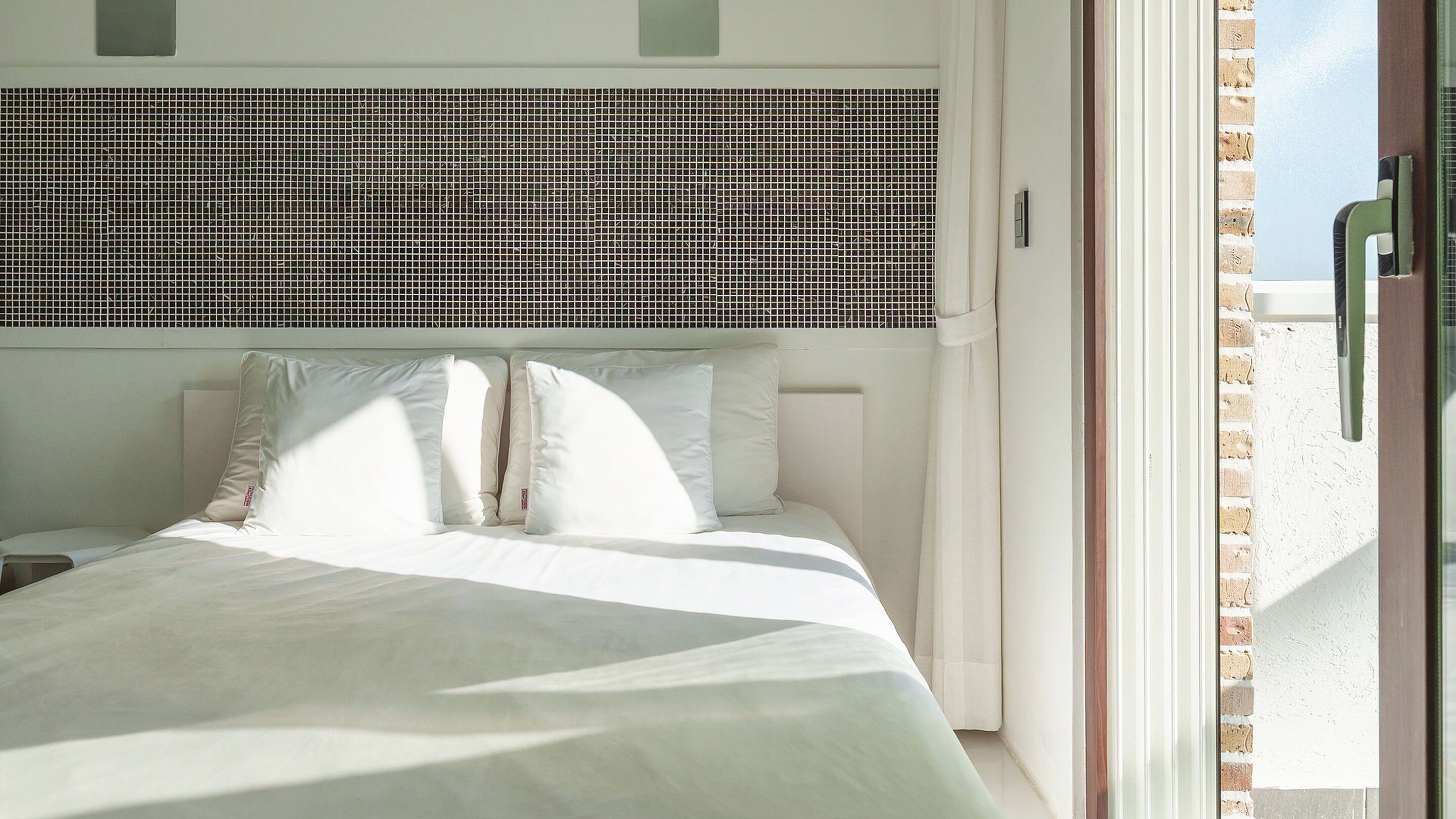 A bed with white bedding and a headboard with a grid pattern.