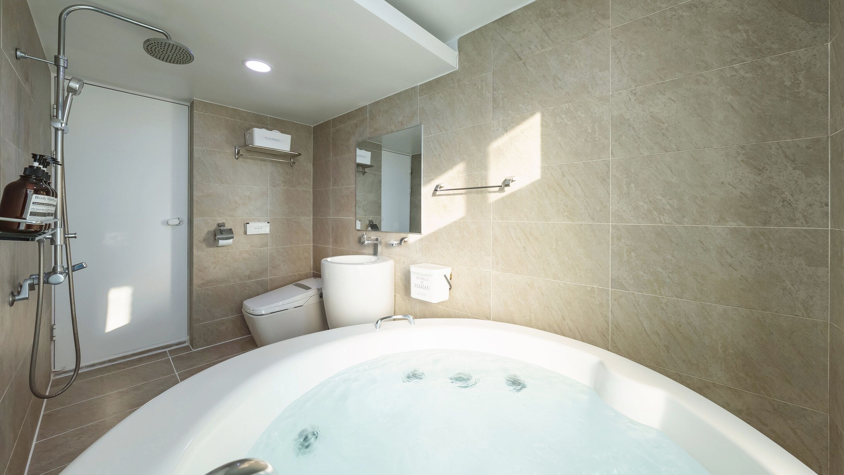 A modern bathroom with a bathtub, toilet, and shower.