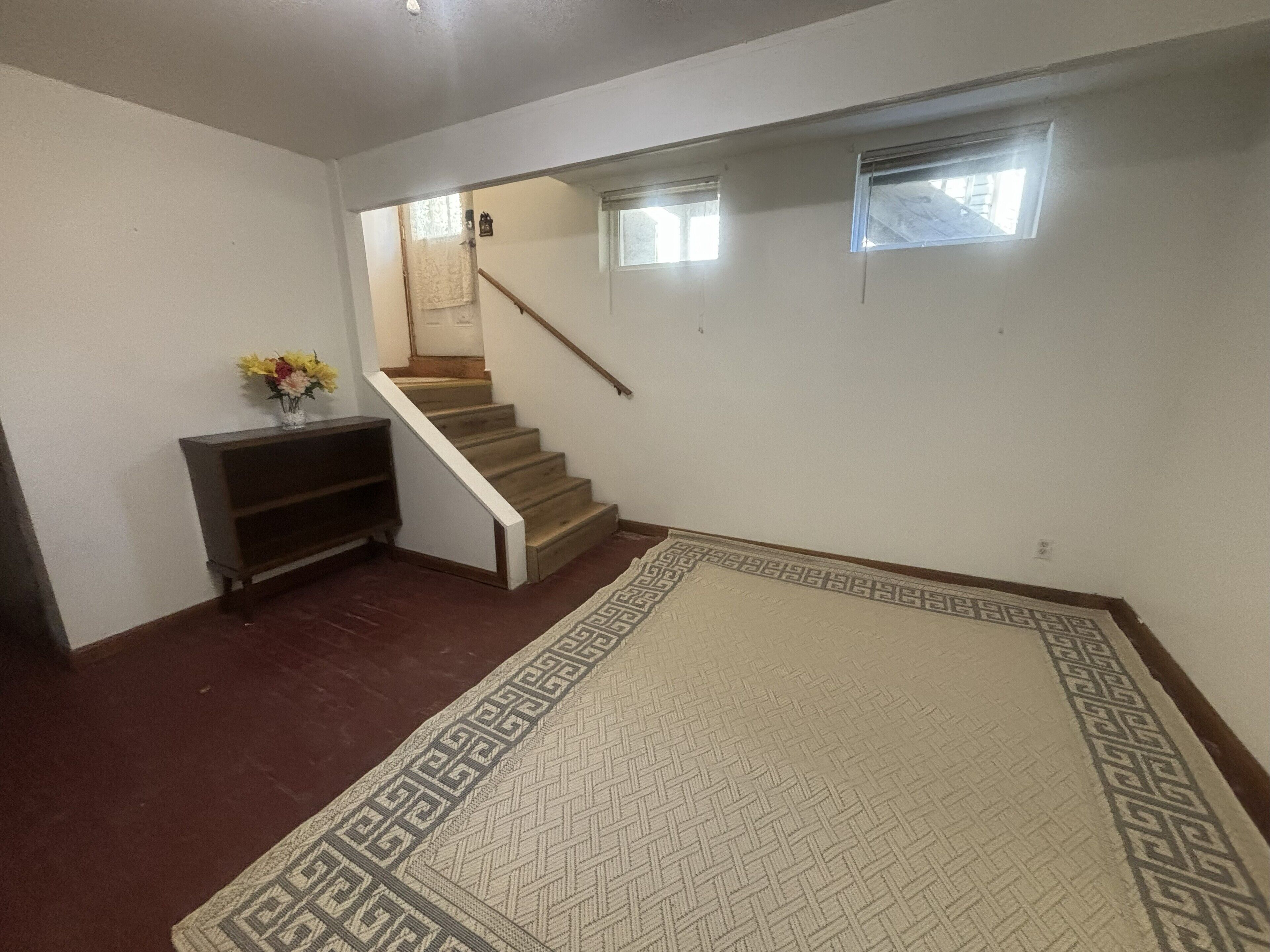 A staircase leading to a landing with a patterned rug and a small table with flowers.