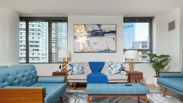 A modern living room with a sofa set, a coffee table, and a large abstract painting on the wall. - Central 2BR Condo in Downtown Boston & T-Station (Boston)