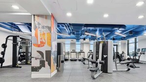 A gym with various exercise equipment, including treadmills and weight machines, and a large mural on the wall. - Central 2BR Condo in Downtown Boston & T-Station (Boston)