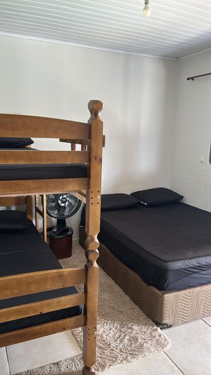 A bunk bed with a wooden headboard, a small fan, and a mattress on the floor. - House with a Pool in Caraguatatuba (Caraguatatuba)