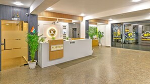 A modern reception area with a reception desk labeled "HELPDESK I AM HERE TO HELP YOU," a sign for the office, and a coffee shop named "Sky Espresso."
