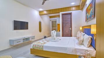 Una habitación de hotel moderna con cama, lámparas de noche, ventilador de techo, televisor, espejo y puerta de madera.