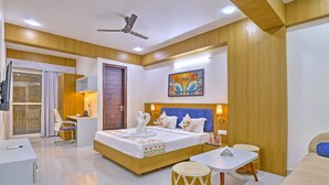 Una habitación de hotel moderna con una cama grande, mesitas de noche, un ventilador de techo y un cuadro en la pared.