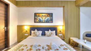 A hotel room with a large bed, two bedside lamps, a painting of swans, and a small round table.