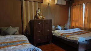 Ein Hotelzimmer mit zwei Betten, einem Kleiderschrank, einer Buddha-Statue und einer Wand-Klimaanlage.