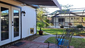 A house with a covered patio, a door with glass panels, a small garden with a bench, and a wheelbarrow.