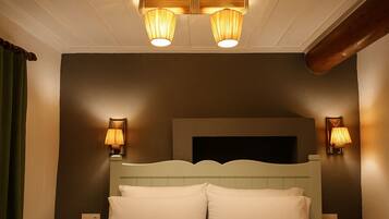 A hotel room with a bed, two wall-mounted lamps, and a ceiling light fixture.