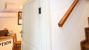 Una scala con ringhiere in legno e una porta bianca con maniglia nera.