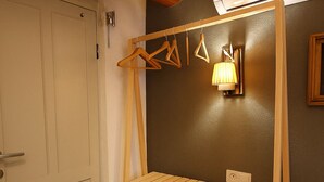 Una stanza con un armadio in legno, un appendiabiti e una lampada a parete.