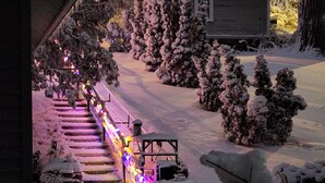 A snow-covered outdoor area with a staircase leading to a building, surrounded by snow-laden trees.