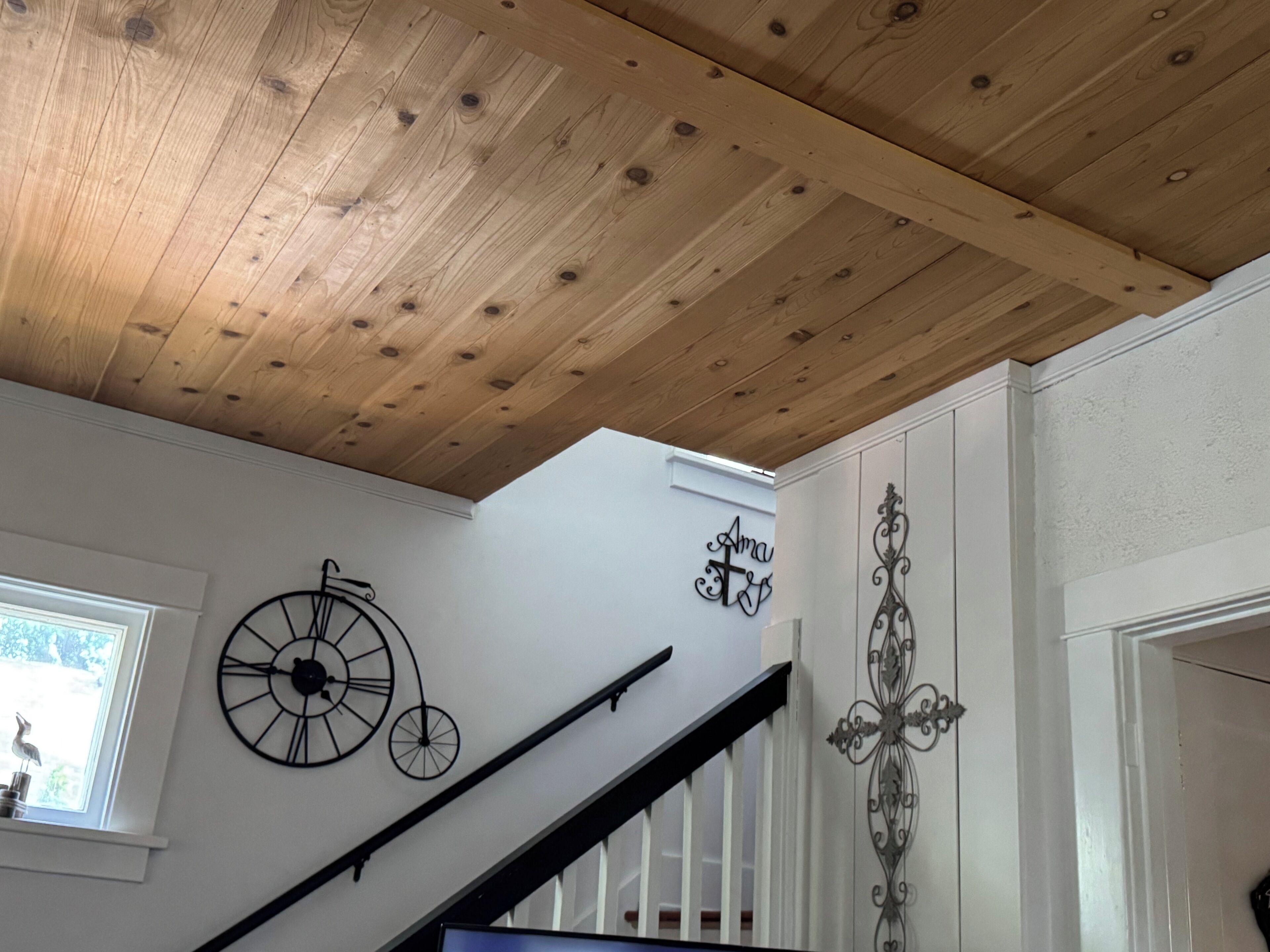 Una scala con soffitto in legno, una sveglia a parete e decorazioni in metallo.