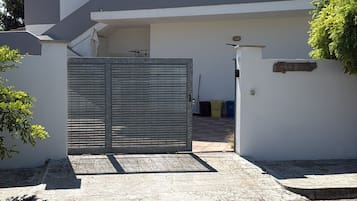 Un bâtiment moderne à deux étages, doté d’une entrée sécurisée par un portail, d’un toit plat et d’un appareil de climatisation visible.