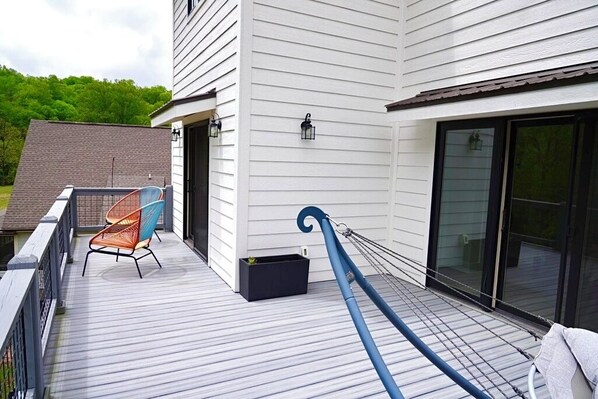 Una terraza con una silla, un caja de almacenamiento negro y un paraguas azul.