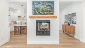 A modern living room with a fireplace, a kitchen in the background, and a dining area. - Tower on the Tuck: Entire home on the Tuckaseegee River near WCU -Riverfront (Cullowhee)