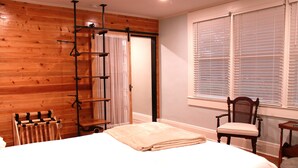 A bedroom with a wooden floor, a bed with a white comforter, a wooden chair, a radiator, and a window with blinds. - Reconnect with Nature Farmhouse sleeps 6, two large bathrooms, full kitchen, (Whiteville)
