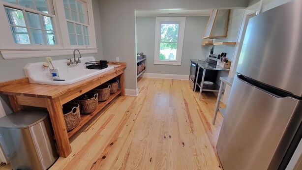 A modern kitchen with a wooden countertop, stainless steel appliances, and a view of the outdoors. - Reconnect with Nature Farmhouse sleeps 6, two large bathrooms, full kitchen, (Whiteville)