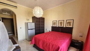 Une chambre à coucher avec un grand lit, une armoire, un bureau et un luminaire suspendu.