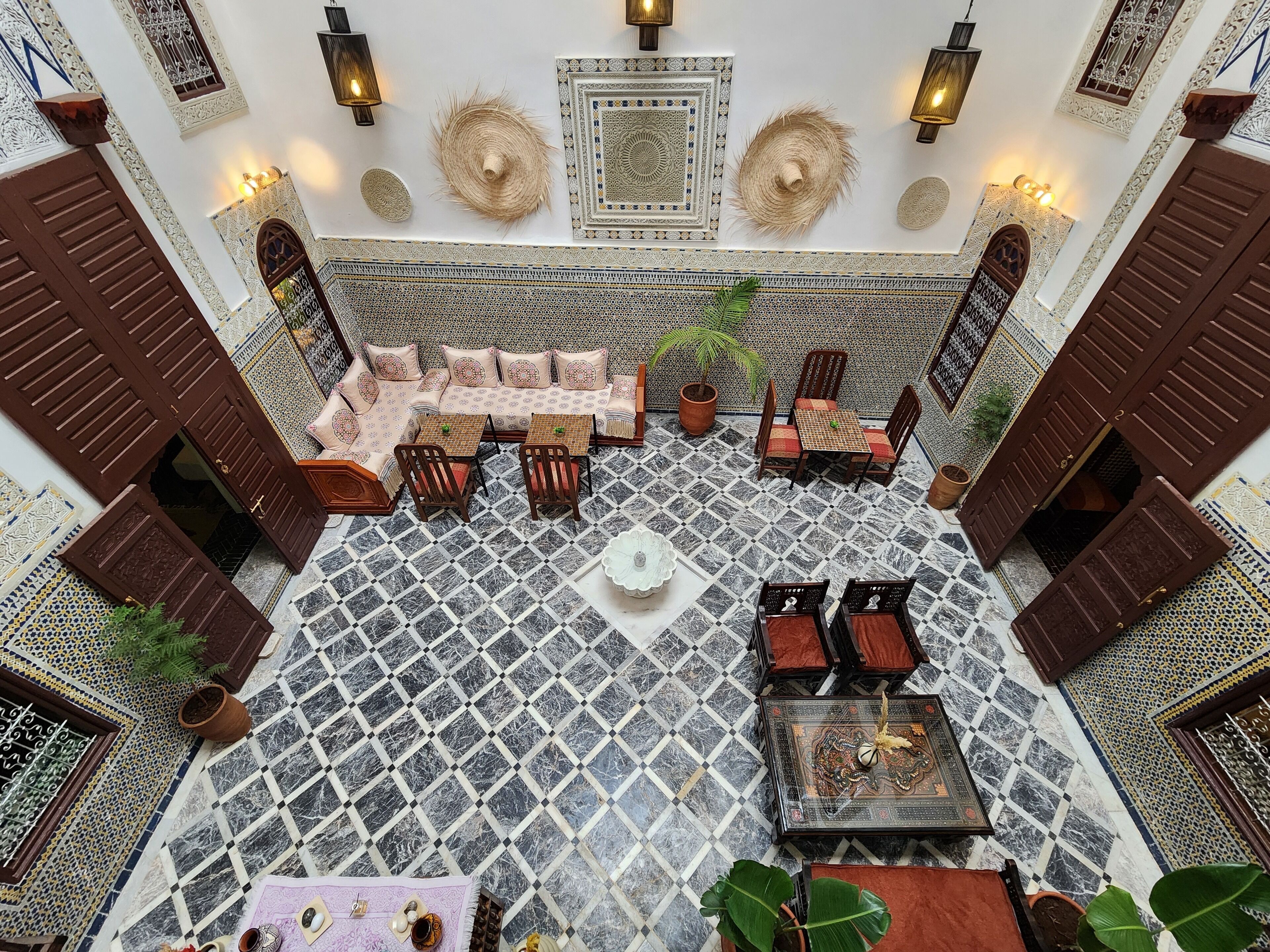 A spacious courtyard with a patterned floor, seating areas, and decorative wall elements.