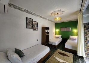 A room with two single beds, a wardrobe, a ceiling fan, and a patterned floor. - Riad Dar Mazaj Fes (Fes)