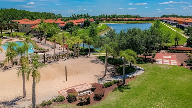 A resort with a swimming pool, palm trees, and a large body of water. - Bella Vida Cozy 3bd/3ba King Bed Private Pool (Kissimmee)