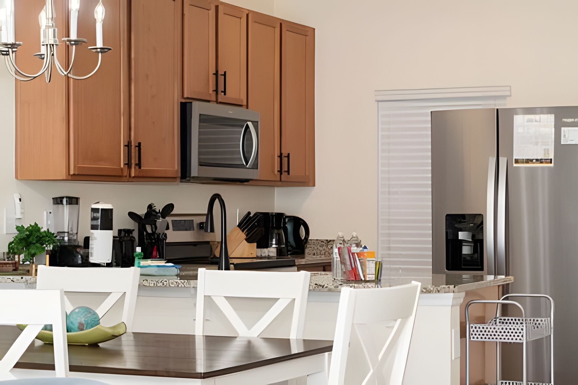 Una cocina moderna con armarios de madera, microondas, cafetera y refrigerador.