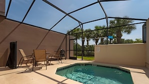 An indoor swimming pool with a clear view of the surrounding area, including a covered patio with chairs and a table. - Bella Vida Cozy 3bd/3ba King Bed Private Pool (Kissimmee)