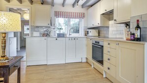 Una cocina moderna con armarios blancos, horno integrado y ventana con cortina a rayas.