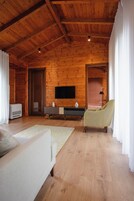 Una habitación con paneles de madera, un sofá, una silla, un televisor y una mesita.