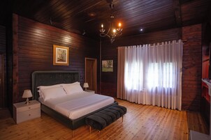 Un dormitorio con paneles de madera, una cama grande, mesitas de noche, un banco y un candelabro.